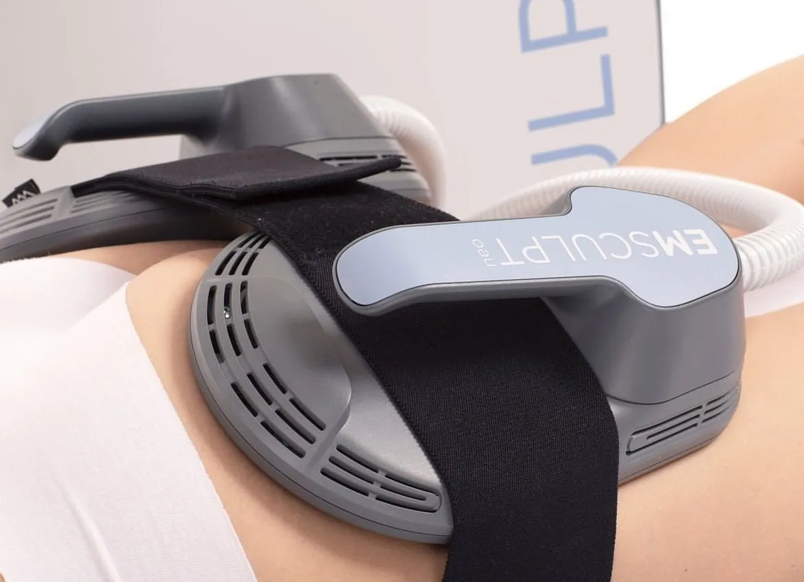 Close-up of a person's abdomen with an Emsculpt Neo device strapped on, used for non-invasive body contouring and muscle toning treatment.
